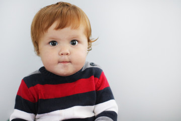 Portrait of cute one year old boy with ginger hair and blue eyes