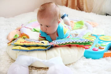 Fotobehang Cute little baby reading a boog among toys © Ekaterina