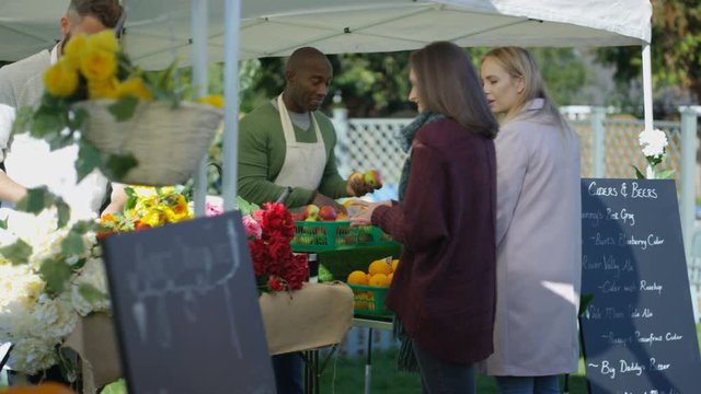  Friendly stall holders selling to customers at a farmers market