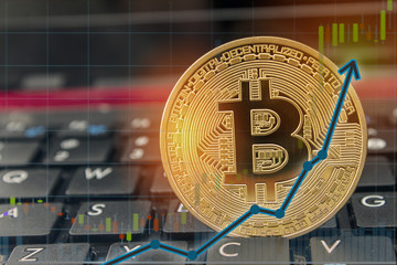 Bitcoin currency rising concept on laptop keyboard with up arrow chart and golden bitcoin. ...