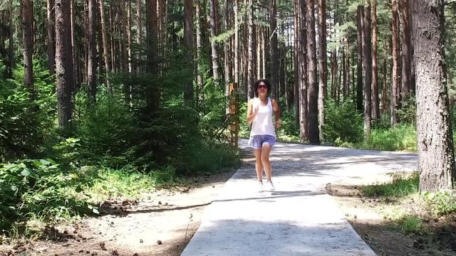 Runner woman running in forest park exercising outdoors, SLOW MOTION