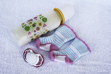 Set for newborn girl with baby milk, toy, pacifier and cute little  socks on white background.