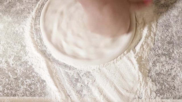 The process of cooking pizza by a cook in a restaurant. A piece of raw pizza dough falls on the table into flour. 4K.
