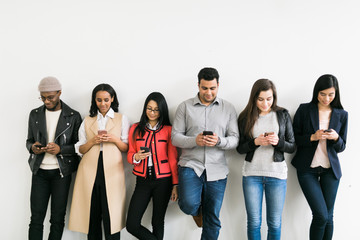 Obraz premium Young men and women looking at their cell phones