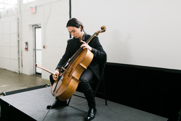 Young man on stage playing the cello