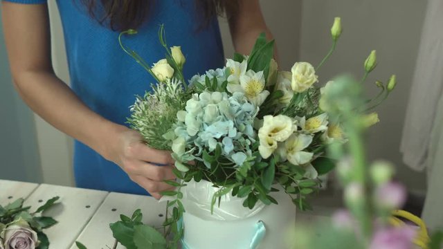 Florist composes the composition in the hat box close-up 4k.