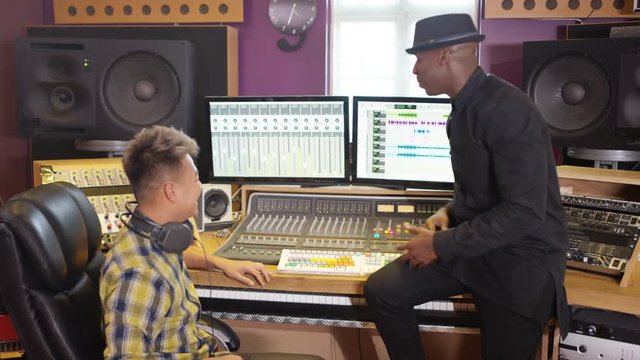  Music producer & sound engineer working together in recording studio