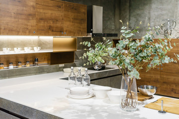 Modern kitchen interior design with wooden facades and granite worktop and white cupboards