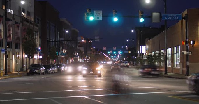 A night time lapse view establishing shot of traffic and buildings along East Carson Street in Pittsburgh's South Side district.  	