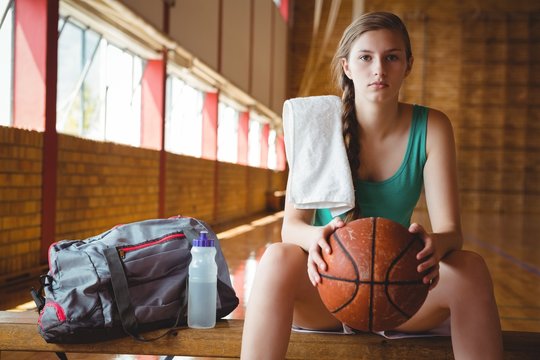 Portrait of female basketball player sitting on bench