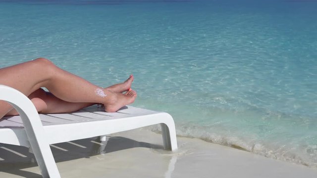 Woman relax on white plastic sunbed at perfect calm beach with crystal and turquoise sea water. Vacations on Maldivian Island