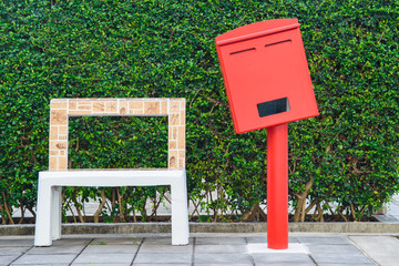 Red post box and stone chair on tree background - 173861460