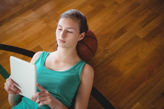 Female basketball player using digital tablet while relaxing in
