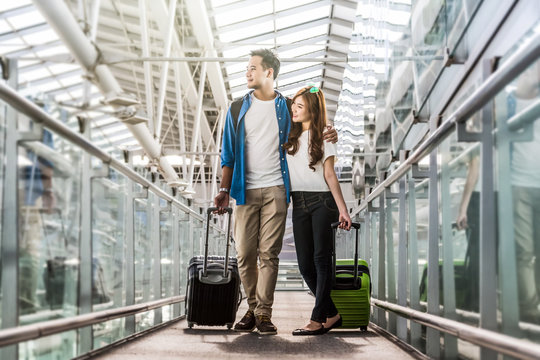 Asian couple traveler with suitcases at the airport. Lover travel and transportation with technology concept.