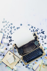 Writer workplace with scattered letters stationery and a typewriter. Crumpled paper balls with pencils on a white wooden background, creative writing concept. Flat lay with copy space.