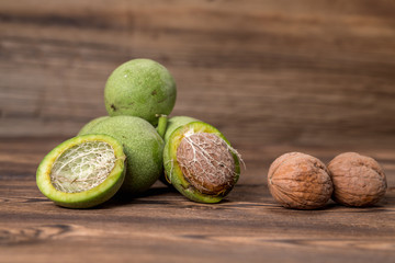 Fresh harvest of walnuts on a wooden background. Green and brown nuts. Shell and peel of walnuts. Walnuts on a wooden surface
