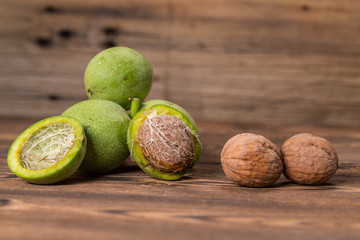 Fresh harvest of walnuts on a wooden background. Green and brown nuts. Shell and peel of walnuts. Walnuts on a wooden surface