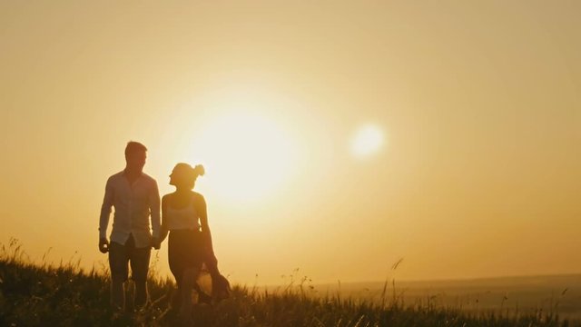 Loving couple - brave young man and beautiful girl at sunset silhouette, slow-motion