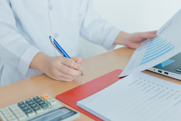 Health care costs concept picture : Hand of female doctor used a calculator for medical costs. Stethoscope and calculator on a medical chart ,symbol for health care costs or medical insurance.
