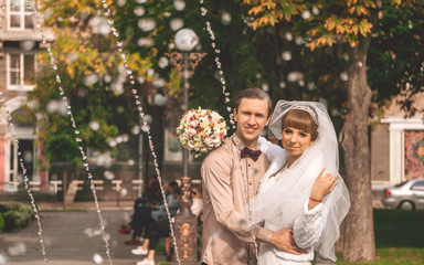 Festive wedding day. Joyful groom and bride in a city park