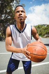 Male teenager practicing basketball