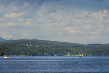 man paddling in is kayak on quebec memphremagog lake with Saint Benedict Abbey in front
