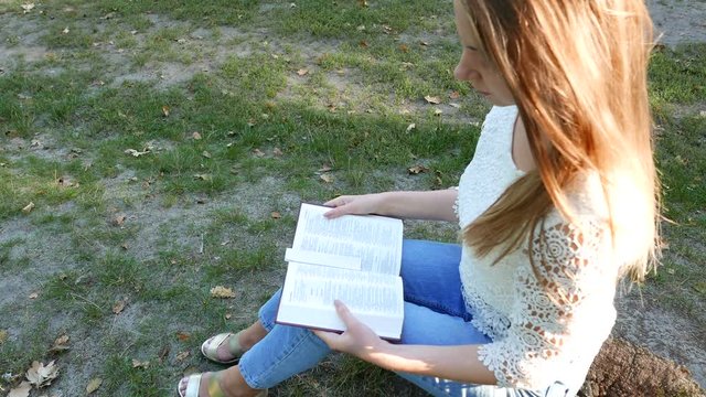 4k. Bible  and attractive girl in sunny park. Christian prayer team shot, top view