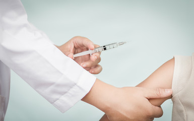 Doctor holding a syringe with a liquid inside next to a girl arm.