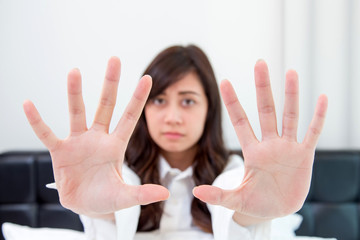 Portrait of a young attractive woman showing stop sign with hand on her bedroom