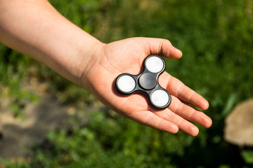 Boy playing with fidget spinner stress relieving toy outdoor