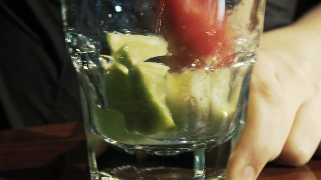 Caipiroska coktail. The barman presses the lime in a glass.