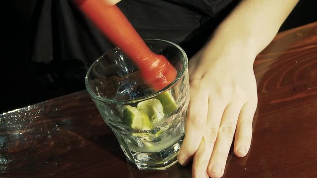 Caipiroska coktail. The barman presses the lime in a glass.