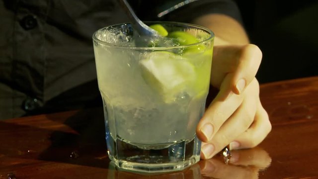 Caipiroska coktail. The bartender mixes the cocktail.