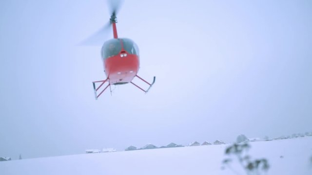 Helicopter flying over a snowy landscape, showcasing the vibrant red color against the white snow, capturing the essence of winter aviation and adventure in a serene environment