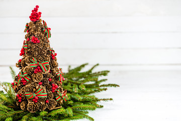 Pine cone christmas tree background with red holly and fir on white wooden board