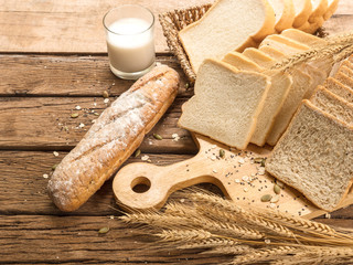 Bread bun and a glass of fresh milk on wooden background for morning meal, still life