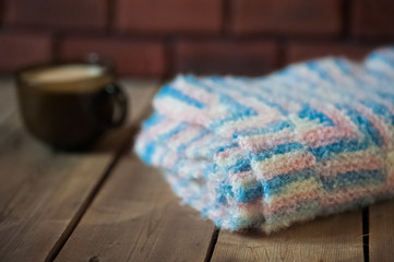 The knitted plaid of a multi-colored wool. Handmade. Heat of the home. Plaid and a cup of coffee or cocoa