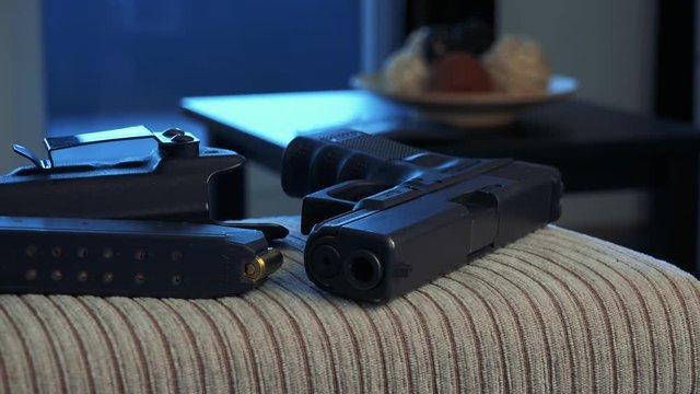 Handgun with magazine and holster lies on sofa in living room in home