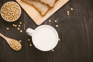 Glass with soy milk and soy bean on wooden background