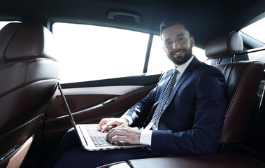 young businesswoman working on her laptop while sitting in the car