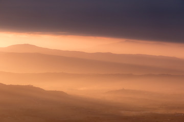 A valley filled by mist at sunset, with emerging hills and beautiful warm, orange tones