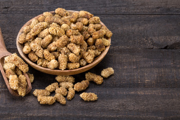 Close Up Shot Of Dried White Mulberries Fruits In A Wooden Bowl And Spoon On Dark Wooden Background And Empty Space For Typing Text