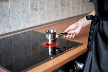 A picture of a young wife preparing coffee in the kitchen in the morning