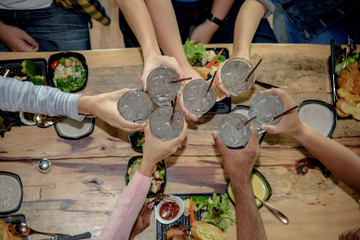 Top view of clinking glasses with drink in hands on job success. Holiday party cheers of friends.