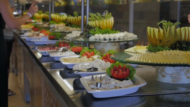 Buffet in the hotel, restaurant. People go to the table and pick up food, cheeses