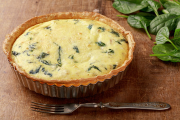 Freshly backed spinach quiche, just from the oven 0n wooden background