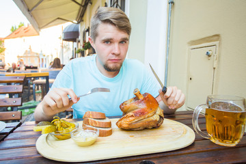 Man eating smoked pork meat and drinking beer