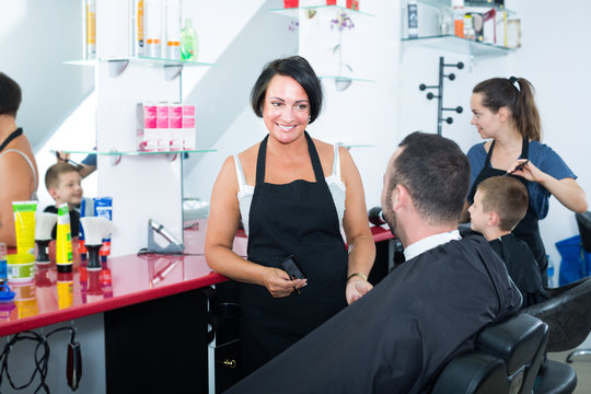 Positive mature woman hairdresser chatting to male