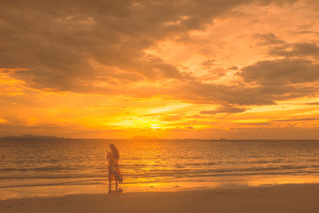 Fototapeta na wymiar Golden scene on the beach at sunset. Tourist girl sefie herself with sunset at the coast.