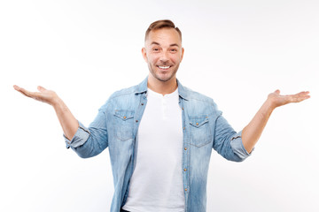 Cheerful young man spreading his hands in amazement
